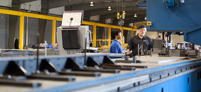 Doyle Blooding and Jeremy Smithes standing near a Friction Stir Welder.